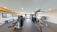 Located at 96 Coco Plum Dr in Marathon, Florida, this single-floor fitness center offers a comprehensive exercise facility designed to accommodate a wide range of workout routines. The space is laid out as one open exercise room with durable rubber flooring throughout, providing both safety and functionality for various types of training.

The cardio zone is well-stocked with multiple treadmills, a stationary spin bike, an elliptical, and a rowing machine, arranged to maximize floor space while maintaining comfortable clearance between equipment. A dedicated strength training area features a multi-station cable machine, additional selectorized weight machines, and a dumbbell rack with a full range of free weights. A stability ball, medicine balls, and a workout bench round out the functional training options.

Large windows along the perimeter allow ample natural light to fill the space and provide views of the surrounding Marathon landscape. Recessed ceiling lighting supplements illumination throughout. Multiple wall-mounted flat-screen televisions are positioned throughout the room for user convenience. A bold orange accent wall adds visual energy to the space. An adjacent locker area with built-in cubbies and seating provides a functional transition zone near the entrance, which features glass-panel doors leading to the exterior.