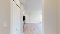 This single-floor residence offers a thoughtfully designed layout encompassing five distinct areas, making efficient use of its compact footprint. Light wood-tone flooring runs continuously throughout, creating a cohesive and airy feel across every room.

The kitchen is a functional highlight, featuring white shaker-style cabinetry, dark granite countertops, a stainless steel sink, and a full suite of stainless steel appliances including a refrigerator, range, and microwave. Recessed lighting and decorative crown molding add a polished touch to the space.

The living area benefits from large, dark-framed windows that frame views of the surrounding urban cityscape, allowing generous natural light to fill the room. A baseboard heating unit runs beneath the windows, providing efficient climate control.

The bedroom is generously proportioned and features a built-in closet with shelving, a large window admitting bright natural light, and the same warm wood flooring found throughout the unit.

The bathroom is cleanly finished with beige tile flooring, a white vanity with brushed nickel hardware, and a full tub-shower combination surrounded by vertically laid white tile. Grab bars and a curved shower rod add practical detail.

Throughout the space, crisp white walls, recessed lighting, and consistent finishes create a clean, move-in-ready environment with a modern and understated aesthetic.