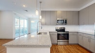 Located in Phoenix, AZ, this well-appointed 2-bedroom, 2-bathroom single-floor residence offers a thoughtfully designed open-concept layout. The kitchen is a standout feature, showcasing sleek gray cabinetry, granite countertops with a large peninsula, pendant lighting, and a full suite of stainless steel appliances including a range, microwave, and refrigerator. Warm wood-style flooring flows seamlessly through the kitchen, living, and dining areas, which are filled with natural light from large windows and a sliding glass door leading to a private balcony with outdoor views.

The dining area features an overhead light fixture and additional window, creating a bright and inviting atmosphere. Both bedrooms are carpeted and generously sized, each with natural light from large windows; the primary bedroom includes a ceiling fan. The bedrooms are served by two full bathrooms, one of which features a dual-sink granite vanity with gray cabinetry, a tub-shower combination with white subway tile, and wood-style flooring. Two closets provide ample storage, including a carpeted walk-in closet with built-in shelving and hanging rods. A dedicated in-unit laundry area with full-size washer and dryer adds everyday convenience.