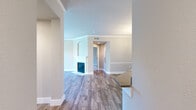 This single-story, 2-bedroom, 2-bathroom home offers a thoughtfully designed layout with a neutral color palette and wood-look flooring throughout the main living areas. The open living room serves as the heart of the home, featuring crown molding, a classic white-mantled fireplace with an arched decorative surround, and a window that fills the space with natural light. Adjacent to the living area, the dining room is defined by warm hardwood-style flooring, a stylish pendant chandelier, and chair-rail molding that adds architectural character to the walls. The kitchen is outfitted with white shaker-style cabinetry, sleek quartz countertops, a marble-style subway tile backsplash, and stainless steel appliances. Both bathrooms are finished with contemporary vanities featuring undermount sinks, quartz counters, and warm-toned framed mirrors. The primary bedroom is a comfortable retreat with plush carpet flooring and an arched window overlooking lush greenery, accompanied by a walk-in closet with wire shelving. A dedicated laundry area with washer/dryer hookups adds everyday convenience. Three hallways connect the home's rooms efficiently, completing a practical and polished floor plan.