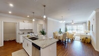 This well-appointed 2-bedroom, 2-bathroom single-floor residence offers a thoughtfully designed open-concept layout that seamlessly connects the kitchen, dining, and living areas. The kitchen is a standout feature, showcasing white shaker cabinetry, granite countertops, a large center island with bar seating and a double sink, pendant lighting, and a full suite of stainless steel appliances including a French door refrigerator, range, microwave, and dishwasher. Rich hardwood-style flooring flows throughout the entire residence, adding warmth and continuity.

The living room is bright and welcoming, with large windows that invite abundant natural light and a ceiling fan overhead. Crown molding adds a refined architectural touch to the common areas. The dining space connects naturally to the living room, creating an ideal layout for entertaining.

Both bedrooms are generously sized with ceiling fans and large windows. The primary bedroom features an en-suite bathroom with granite vanity, white cabinetry, and a walk-in closet. The second bathroom mirrors the same finishes. An additional room serves as a flexible home office space, complete with dual windows. The overall ambiance is clean, modern, and comfortable throughout.