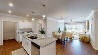 This well-appointed 2-bedroom, 2-bathroom single-floor residence offers a thoughtfully designed open-concept layout that seamlessly connects the kitchen, dining, and living areas. The kitchen is a standout feature, showcasing white shaker cabinetry, granite countertops, a large center island with bar seating and a double sink, pendant lighting, and a full suite of stainless steel appliances including a French door refrigerator, range, microwave, and dishwasher. Rich hardwood-style flooring flows throughout the entire residence, adding warmth and continuity.

The living room is bright and welcoming, with large windows that invite abundant natural light and a ceiling fan overhead. Crown molding adds a refined architectural touch to the common areas. The dining space connects naturally to the living room, creating an ideal layout for entertaining.

Both bedrooms are generously sized with ceiling fans and large windows. The primary bedroom features an en-suite bathroom with granite vanity, white cabinetry, and a walk-in closet. The second bathroom mirrors the same finishes. An additional room serves as a flexible home office space, complete with dual windows. The overall ambiance is clean, modern, and comfortable throughout.