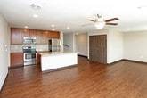 This two-floor residential space offers a well-designed, functional layout with a range of modern finishes throughout. The open-concept main living area features rich hardwood-style flooring and is anchored by a spacious kitchen equipped with warm-toned wood cabinetry, granite-look countertops, a full suite of stainless steel appliances including a range, over-the-range microwave, and refrigerator, and a central island with a sink — ideal for both meal prep and casual dining. A ceiling fan overhead adds comfort to the generous living area that flows seamlessly from the kitchen.

The bedrooms are finished with plush carpeting and ceiling fans, offering a comfortable retreat. Each bedroom benefits from walk-in closet space outfitted with wire shelving systems for organized storage. The bathrooms are clean and practical, featuring dark wood vanities with light countertops, full tub-shower combos, hardwood-style flooring, and well-lit mirrors. Multiple bathrooms serve the space, including one accessible from a hallway near the bedrooms.

A dedicated in-unit laundry room with a full-size washer and dryer adds significant everyday convenience. Dark baseboards throughout create a cohesive, polished aesthetic, tying together the neutral wall tones and varied flooring materials across both levels.