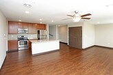 This two-floor residential space offers a well-designed, functional layout with a range of modern finishes throughout. The open-concept main living area features rich hardwood-style flooring and is anchored by a spacious kitchen equipped with warm-toned wood cabinetry, granite-look countertops, a full suite of stainless steel appliances including a range, over-the-range microwave, and refrigerator, and a central island with a sink — ideal for both meal prep and casual dining. A ceiling fan overhead adds comfort to the generous living area that flows seamlessly from the kitchen.

The bedrooms are finished with plush carpeting and ceiling fans, offering a comfortable retreat. Each bedroom benefits from walk-in closet space outfitted with wire shelving systems for organized storage. The bathrooms are clean and practical, featuring dark wood vanities with light countertops, full tub-shower combos, hardwood-style flooring, and well-lit mirrors. Multiple bathrooms serve the space, including one accessible from a hallway near the bedrooms.

A dedicated in-unit laundry room with a full-size washer and dryer adds significant everyday convenience. Dark baseboards throughout create a cohesive, polished aesthetic, tying together the neutral wall tones and varied flooring materials across both levels.