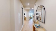 Located at 532 Neptune Ave in Brooklyn's Coney Island neighborhood, this well-appointed 2-bedroom, 2-bathroom residence offers a thoughtfully designed single-floor layout. Light wood flooring flows throughout, complementing a warm, contemporary aesthetic from entry to living area.

The welcoming hallway, accented by a sleek arched mirror, leads into an open-plan living, dining, and kitchen area. The kitchen features warm wood lower cabinetry paired with crisp white upper cabinets, quartz countertops, and stainless steel appliances, including a professional-grade range. The living and dining areas offer an airy feel, with large sliding glass doors opening onto a private balcony that frames open city and sky views.

Both bedrooms are bathed in natural light through floor-to-ceiling windows with urban views. The rooms are finished with calming blue-toned accent walls and light hardwood floors, creating a serene retreat. Four closets throughout the unit provide generous storage.

The two bathrooms are finished to a high standard — one features a glass-enclosed soaking tub and tub/shower combo with warm wood vanity and a backlit oval mirror, while the primary en-suite offers a frameless glass walk-in shower, floating vanity, and large-format tile. An in-unit laundry room adds everyday convenience.