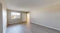 This single-floor residence offers a practical and cohesive layout across two bedrooms, two bathrooms, a living room, kitchen, hallway, and utility room. Light gray laminate flooring runs consistently throughout the space, complemented by neutral warm-gray walls and crisp white trim, creating a clean and unified aesthetic.

The living room is a welcoming open area bathed in natural light from a large front-facing window, with a textured ceiling and direct access to the rest of the unit. Both bedrooms are well-proportioned, with the primary bedroom offering generous closet space and a window overlooking greenery. The second bedroom also benefits from natural light and shares the same consistent flooring and neutral palette.

The galley-style kitchen is efficiently organized, featuring white cabinetry on both sides, white appliances including a range and refrigerator, light countertops, and a utility door at the far end — providing excellent storage and workflow in a compact footprint.

Both bathrooms mirror each other in design, each equipped with a white vanity with shaker-style cabinet doors, a single-basin sink, a bathtub, and a wall-mounted mirror with overhead lighting. The light wood-tone flooring ties seamlessly into the rest of the home. Overall, the space presents a clean, move-in ready environment with consistent finishes throughout.