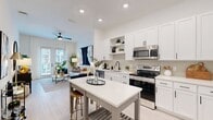 This thoughtfully laid-out one-bedroom, one-bathroom unit at 900 E Sligh Ave offers a cohesive modern aesthetic throughout its single-floor footprint. The open-concept kitchen is a standout feature, showcasing white shaker cabinetry, a subway tile backsplash, stainless steel appliances including a refrigerator with ice maker, electric range, microwave, and dishwasher, all complemented by light wood-look flooring. A freestanding kitchen island with seating provides additional prep and dining space.

The living room is bright and welcoming, featuring large windows with sheer curtains, a ceiling fan, and light-toned walls that enhance the sense of openness. The space flows naturally from the kitchen and entry area.

The primary bedroom offers carpeted flooring, a ceiling fan, and generous window placement that brings in natural light. It is served by a dedicated closet and connects to the full bathroom, which features a walk-in glass-enclosed shower with tile surround, a white vanity with under-mount sink, black hardware accents, and light wood-look flooring. The clean, neutral palette carries consistently throughout the unit, creating a modern and cohesive living environment.