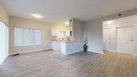This well-appointed single-floor residence offers a clean, modern aesthetic with a thoughtfully designed open-concept layout. The expansive living area is bathed in natural light, courtesy of large windows dressed with vertical blinds, creating an airy and inviting atmosphere. Wood-style luxury flooring flows seamlessly throughout the space, complementing the neutral gray and beige tones on the walls.

The kitchen is a standout feature, showcasing crisp white shaker-style cabinetry, granite-look countertops, and a peninsula that opens directly to the living area — ideal for both everyday living and entertaining. Stainless steel appliances, including a dishwasher and refrigerator, add a contemporary touch, while a window above the sink provides additional natural light.

The bedroom is generously proportioned with vaulted ceilings, a ceiling fan, and large windows offering views of lush outdoor greenery, along with a closet providing ample storage. The bathroom features a full tub-and-shower combination with clean white tile surround and brushed nickel fixtures.

Practical features include an in-unit laundry nook housing a washer and dryer, as well as additional closet storage. The overall design is clean, functional, and move-in ready, with a bright and welcoming ambiance throughout.