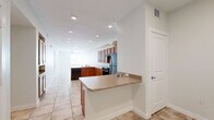 This well-appointed 3-bedroom, 2-bathroom single-story home offers a functional and comfortable layout designed for everyday living. The open-concept kitchen serves as the heart of the home, featuring warm-toned wood cabinetry, black appliances including a refrigerator and range, a built-in peninsula with countertop seating, recessed lighting, and a sink with ample counter space. Light ceramic tile flooring flows consistently throughout the entire home, creating a clean and cohesive aesthetic.

The living area extends generously from the kitchen, bathed in natural light and illuminated by recessed ceiling fixtures. Each of the three bedrooms is well-sized, with the primary bedroom offering notable square footage, ceiling fans, and access to natural light through windows with views of surrounding greenery. Two additional bedrooms are similarly bright and comfortable, each with ceiling fans and tile flooring.

The two bathrooms are thoughtfully designed, with one featuring accessibility grab bars, a walk-in shower, a wood-vanity with countertop sink, and a window for natural light. Storage is well-addressed throughout, with three dedicated closets, including a spacious walk-in closet equipped with wire shelving. A central hallway connects all rooms, contributing to the home's efficient and easy-to-navigate floor plan.