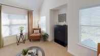 This two-story home offers a well-organized and functional layout designed for comfortable everyday living. The main level features an open-concept living area with vaulted ceilings, soft carpeting, and generous natural light streaming through multiple windows. A built-in niche provides a natural focal point for display or storage. The adjacent dining area is highlighted by track lighting and a wall mirror that enhances the sense of space. The galley-style kitchen is outfitted with stainless steel appliances, dark granite-style countertops, white cabinetry, and hardwood flooring, with a window that brings in additional light. The space accommodates multiple bedrooms, each featuring plush carpeting, ceiling fans, and ample natural light from well-positioned windows. The primary bedroom includes room for a seating area and benefits from a spacious, elongated en-suite bathroom with a long vanity, dark countertops, white cabinetry, and tile flooring. A secondary bathroom features a full tub and shower combination with tile surround. Throughout the home, a consistent palette of white walls, neutral tones, and warm wood accents creates a cohesive and inviting atmosphere across both floors.
