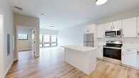Located at 27S Main St in Attleboro, Massachusetts, this well-appointed one-bedroom, one-bathroom residence offers a thoughtfully designed open-concept layout with modern finishes throughout. Light hardwood flooring flows seamlessly across the entire unit, lending warmth and continuity to every room.

The combined kitchen and living area serves as the heart of the home. The kitchen is outfitted with crisp white shaker cabinetry, a classic white subway tile backsplash, quartz countertops, and a central island ideal for dining or food preparation. Stainless steel appliances — including a refrigerator, range, microwave, and dishwasher — complete the sleek, contemporary look.

The living area benefits from an expansive bank of floor-to-ceiling windows framing views of the surrounding Attleboro streetscape, filling the space with generous natural light.

The bedroom is a comfortable and quiet retreat, also featuring large windows that bring in ample daylight and outdoor views. A dedicated closet provides practical storage. The bathroom is finished in a clean, all-white palette with a shaker-style vanity, quartz countertop, and mirrored medicine cabinet. A utility room rounds out the functional layout of this efficiently designed residence.