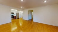 Located at 1400 Worcester Rd in Framingham, MA, this single-floor residence offers a thoughtfully designed layout that balances open living space with functional room separation. Warm-toned hardwood flooring flows consistently throughout, lending a cohesive and inviting feel to the entire unit.

The open living and dining area is generously proportioned, featuring recessed lighting, crown molding, and baseboard heating that runs along the perimeter. An adjacent room provides additional flexible living space, also finished with matching hardwood floors, crown molding, and a wall-mounted light fixture. A window fitted with vertical blinds allows for natural light and ventilation via a wall air conditioning unit.

The kitchen is a standout feature, outfitted with a full suite of stainless steel GE appliances including a refrigerator, electric range, over-the-range microwave, and dishwasher. Two-tone cabinetry pairs rich wood-toned lower cabinets with crisp white upper cabinets, complemented by light countertops and a single-basin sink. The layout is efficient and well-lit with overhead fluorescent lighting.

The bathroom is finished in an all-white palette, featuring a vanity with white cabinetry, a tiled tub-and-shower combination with a curved curtain rod, and marble-look tile flooring, offering a clean and polished aesthetic throughout.