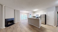This single-floor residence at 10 Gentrys Walk in Atlanta, Georgia offers a thoughtfully designed open-concept layout with a neutral color palette and wood-style flooring throughout the main living areas. The living room serves as a welcoming focal point, anchored by a striking black-tiled fireplace and a decorative white column, with natural light streaming in through multiple windows that frame views of lush greenery outside.

The kitchen is well-appointed with white cabinetry, granite-style countertops, a tile backsplash, and a full suite of stainless steel appliances including a gas range and a full-size refrigerator. A peninsula counter connects the kitchen seamlessly to the dining and living areas, making it ideal for entertaining.

The bedrooms feature plush carpeting and neutral tones, with windows that invite natural light. The primary suite includes an en-suite bathroom with a granite-topped vanity, wood-style flooring, and access to a walk-in closet. A secondary bathroom offers a full tub-shower combination with clean white fixtures and modern chrome hardware.

A dedicated in-unit laundry closet houses a full-size washer and dryer with built-in shelving above for added storage. The overall ambiance is clean, bright, and move-in ready, offering comfortable residential living in the Atlanta metro area.