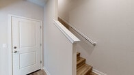 Located in Mountain House, CA, this three-story home offers a clean, modern design with functional living spaces spread across each level. The ground floor houses an attached garage with a spacious concrete floor, automatic opener, and ample room for vehicles and storage. The main living level features an open-concept kitchen and living area highlighted by light hardwood-style flooring, recessed lighting, and a well-appointed kitchen with white shaker cabinetry, dark countertops, a subway tile backsplash, stainless steel appliances including a French door refrigerator, and a central island. The living area includes a dedicated media niche with built-in outlets. The upper floors host four bedrooms, each with ceiling fans and either plush carpet or hardwood-style flooring. Bedrooms feature generous closet space with sliding panel doors and windows that invite natural light and neighborhood views. The four bathrooms are finished consistently with wood-look flooring, white cabinetry, dark countertops, and brushed nickel fixtures — some featuring tub-shower combinations with white tile surrounds. Neutral tones, clean lines, and recessed lighting throughout give the home a cohesive, contemporary feel.