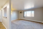 Located at 10623 E Exposition Ave in Aurora, Colorado, this one-bedroom, one-bathroom unit offers a practical and efficient single-floor layout. The living room is a bright, open space featuring neutral-toned carpet, smooth ceilings, and a wall-mounted air conditioning unit. Natural light enters through a large picture window dressed with drape panels, and a baseboard heating system runs along the exterior wall. A pass-through opening connects the living area to the kitchen, which features white cabinetry, a white electric range, and a countertop with sink — providing an open, functional connection between the two spaces. The hardwood-style flooring in the kitchen adds a contrasting warmth to the carpeted common areas. The bedroom offers a comfortably sized retreat with carpet flooring, a large window with outdoor views, a baseboard heater, and a built-in closet with bifold doors providing ample storage. The bathroom is clean and straightforward, featuring a full tub and shower combo with white tile surround. Throughout the unit, neutral wall tones and consistent trim work lend a cohesive, move-in-ready feel to this well-maintained Aurora residence.