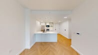Located at 163 Willoughby Street in the heart of Downtown Brooklyn, this thoughtfully designed three-bedroom, two-bathroom residence offers a clean, contemporary aesthetic throughout. Warm herringbone hardwood flooring flows seamlessly across every room, anchoring the modern design palette of crisp white walls and black-accented fixtures and hardware.

The open-plan kitchen and living area serves as the heart of the home. The kitchen is outfitted with a large center island featuring a white quartz countertop and light blue cabinetry, a stainless steel refrigerator, a gas range, and upper glass-front cabinets illuminated by sleek pendant lighting. Recessed lighting and under-cabinet accents add warmth to the space.

Each of the three bedrooms is bright and well-proportioned, with the primary bedroom and at least one additional bedroom benefiting from oversized, floor-to-ceiling windows that frame sweeping views of the Brooklyn and Manhattan skylines, flooding the rooms with abundant natural light.

The two bathrooms are finished with upscale tile work, wood-toned vanities with black metal frames, and glass-enclosed tub-shower combinations featuring multiple shower fixtures and built-in shelving — delivering a spa-like atmosphere. The overall ambiance of the residence is modern, light-filled, and polished, making excellent use of its well-planned layout.
