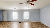 Located at 191 Railroad Street in Enigma, Georgia, this single-story, 3-bedroom, 1-bathroom home offers a practical and straightforward layout across one level. The open-concept living, dining, and kitchen area forms the heart of the home, finished with stone-patterned tile flooring and multiple windows dressed with blinds that allow natural light to fill the space. A ceiling fan with a light fixture adds both function and airflow to the main living area. The kitchen is equipped with white cabinetry — both upper and lower — a white electric range, a refrigerator, an under-cabinet range hood, and a corner sink with countertop space, offering a complete and utilitarian cooking environment. The bathroom features a vanity with under-sink storage, a mirror cabinet, and tile flooring consistent with the main living areas. Each of the three bedrooms is finished with wood-look laminate or hardwood flooring in varying warm tones, light blue-gray walls, and individual windows that bring in natural light and outdoor views. One bedroom includes a closet and access to a laundry area. A dedicated laundry space and an additional closet round out the home's functional amenities, making this property a compact yet complete residence.