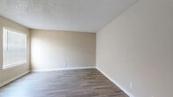 This 2-bedroom, 1-bathroom residence in Irving, Texas offers a well-organized single-floor layout designed for comfortable everyday living. The interior is finished with warm, neutral-toned walls and wood-look tile flooring that flows consistently through most of the space, creating a cohesive and easy-to-maintain aesthetic. Textured ceilings are present throughout, adding subtle architectural character to each room.

The kitchen is a functional highlight, featuring crisp white shaker-style cabinetry, granite-look countertops, a tile backsplash, and black appliances including a refrigerator and range. Ample cabinet storage and counter space make this kitchen both practical and visually appealing.

The combined kitchen and living area provides an open, connected feel. The living room is carpeted and benefits from a ceiling fan with integrated lighting, as well as large vertical-blind-covered sliding doors that invite natural light and offer outdoor access.

The primary bedroom is a well-proportioned space with wood-look flooring and two windows fitted with horizontal blinds, allowing for natural light and outdoor views. The second bedroom is similarly finished with a single window. A dedicated hallway and closet add to the unit's organizational utility.

The bathroom is cleanly appointed with wood-look tile flooring, white cabinetry with brushed nickel hardware, granite countertops, and a full tub-shower combination.