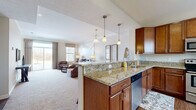 This two-story home offers a thoughtfully designed layout across two floors, combining functional living spaces with quality finishes throughout. The main floor features an open-concept kitchen, dining, and living area that flows seamlessly together. The kitchen is equipped with rich warm-toned cabinetry, granite countertops, stainless steel appliances including a range, microwave, refrigerator, and dishwasher, and hardwood-style flooring. A granite-topped island with pendant lighting bridges the kitchen and the carpeted living and dining areas, which are bathed in natural light from large windows. A dedicated laundry room with full-size washer and dryer hookups and utility sink adds everyday convenience on the main level.

Upstairs, the generously sized primary bedroom features vaulted ceilings, plush carpeting, multiple windows, and a walk-in closet with wire shelving. Two additional bedrooms provide ample space, each with their own closets. All three bathrooms mirror the home's consistent design language, featuring granite vanity tops, warm wood cabinetry, tile flooring, and tub-shower combinations. With three dedicated closets throughout, storage is plentiful. The home's neutral palette, quality finishes, and well-proportioned rooms create a comfortable and cohesive living environment.