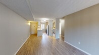 Located at 43205 16th St W in Lancaster, California, this single-story unit offers a thoughtfully arranged layout with a seamless flow between its main living spaces. The open-concept living and dining area is finished with wood-look laminate flooring and neutral gray walls, creating a bright, versatile environment. A textured ceiling runs throughout the common areas, adding a classic residential character. Natural light filters in through windows fitted with vertical blinds, enhancing the airy feel of the space.

The kitchen is positioned adjacent to the living area and features a peninsula-style counter that separates the two spaces while maintaining visual connectivity. It is equipped with stainless steel appliances, including a full-size refrigerator, gas range, and over-the-range microwave, complemented by gray cabinetry and light countertops. Wood-look flooring continues into the kitchen, maintaining design consistency throughout.

A built-in shelving unit between the living area and a secondary room provides additional storage and display space. The bedroom is carpeted and receives natural light through a window with vertical blinds. Mirrored closet doors in one of the rooms add a sense of depth to the space.

The bathroom is clean and functional, featuring a tub and shower combination with brushed nickel fixtures, a single-sink vanity with gray cabinetry, and wood-look flooring.