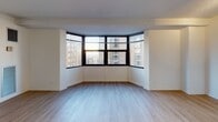 Located at 1133 N Dearborn Street in Chicago's prestigious Gold Coast neighborhood, this single-floor unit offers a well-designed layout with clean, contemporary finishes. Light-toned hardwood flooring runs throughout the main living areas, creating a warm and cohesive aesthetic. The open living space is anchored by a striking curved bay window with dark-framed panes that frames panoramic views of the surrounding Chicago skyline, flooding the room with natural light. A pass-through window connects the living area to the kitchen, maintaining an open and airy feel. The kitchen features white upper cabinetry, light countertops, a stainless steel sink, and a full suite of black appliances including a range, over-the-range microwave, and refrigerator, all set above light hardwood flooring. A hallway leads from the living area to the rest of the unit, providing a clear and functional flow between spaces. The bathroom is finished with a dark espresso-toned vanity, a gray countertop, an integrated white sink, a large mirror, chrome fixtures, and classic black-and-white tile flooring, giving it a timeless and polished look. Overall, the unit presents a clean, modern interior well-suited to urban living in one of Chicago's most sought-after neighborhoods.