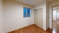 Located at 5246 Brooklyn Ave NE in Seattle's University District, this 2-bedroom, 1-bathroom unit offers a well-designed, efficiently planned single-floor layout. The galley-style kitchen is a standout feature, showcasing dark espresso cabinetry, quartz countertops, a mosaic tile backsplash, and a full suite of stainless steel appliances including a refrigerator, electric range, and microwave. Track lighting illuminates the kitchen corridor, which flows naturally toward the living area. Warm wood-style flooring runs throughout the main living spaces, adding continuity and a modern feel. Both bedrooms are bright and functional, each featuring a window with blinds that brings in natural light, a dedicated closet, and a wall-mounted heating unit. The rooms offer a clean, neutral palette well-suited for personalization. The combined bathroom and laundry room is a practical highlight, housing a stacked washer and dryer unit alongside a shower, toilet, and a vanity with quartz countertops and dark cabinetry matching the kitchen aesthetic. Overall, the unit presents a cohesive modern design with efficient use of space throughout.