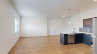 Located on Germantown Avenue in Philadelphia's historic 19144 corridor, this thoughtfully designed one-bedroom, one-bathroom unit offers a clean, modern aesthetic across a well-utilized single floor. The open-concept kitchen and living area serves as the heart of the home, anchored by a sleek kitchen featuring dark flat-front cabinetry, white quartz countertops, a gray subway tile backsplash, stainless steel appliances, and a central island with a built-in sink and pendant lighting overhead. Warm hardwood-style flooring flows seamlessly throughout the entire unit, complementing the bright white walls and creating a cohesive, contemporary feel. The living area is generously proportioned and bathed in natural light from multiple windows fitted with blinds. The private bedroom offers a comfortable footprint with a dedicated window, recessed lighting, and direct access to a walk-in closet equipped with built-in shelving and hanging rods. The full bathroom is appointed with large-format tile flooring, a navy vertically-tiled tub-and-shower surround, matte black fixtures, and a warm wood-toned vanity. A dedicated laundry area rounds out the functional layout of this well-appointed unit.