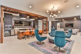 Located in Atlanta, GA, this sophisticated single-floor amenity space delivers a refined blend of modern design and versatile functionality. The layout flows seamlessly across several distinct zones, each thoughtfully appointed with contemporary furnishings and bold design choices.

The kitchen and dining area is a standout feature, boasting dark cabinetry, stainless steel appliances including a wall oven and beverage cooler, a sleek white-topped island with warm wood paneling, and dramatic drum pendant lighting with warm interior tones. A wall-mounted TV adds a media element to the culinary space.

The main lounge area commands attention with a coffered ceiling detail finished in deep charcoal, a textured accent wall, and a centrally positioned circular seating platform anchored by a cylindrical column — creating an inviting social hub. Swivel lounge chairs and curated artwork complete the upscale aesthetic.

The game room offers light hardwood flooring, a billiard table, ping-pong table, wall-mounted televisions, and seating nooks ideal for casual gatherings. Adjacent lounge areas feature leather and upholstered seating arrangements under stylish pendant and recessed lighting.

Additional spaces include a bright co-working nook with counter seating, large windows drawing in natural light, and transitional areas decorated with bold artwork and eclectic furnishings, reinforcing the space's dynamic, urban character throughout.