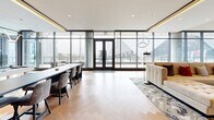 Located at 250 Martin Luther King Jr Dr SW in the heart of Atlanta, Georgia, this upscale single-floor space offers a refined and versatile environment ideal for events, gatherings, or professional use. The open layout spans a generous footprint, designed to accommodate a variety of configurations with ease.

The space is defined by dramatic floor-to-ceiling glass curtain walls and dark-framed double doors that flood the interior with natural light while offering sweeping, unobstructed views of Mercedes-Benz Stadium and the surrounding Atlanta skyline. The herringbone-patterned hardwood flooring runs throughout, lending warmth and a sense of continuity to the open plan.

Distinct functional zones are thoughtfully arranged across the space. A long dining or work table with upholstered chairs anchors one side, while a lounge area features plush seating — including a tufted sofa, bold orange velvet accent chairs, and a round coffee table — arranged to encourage conversation. A built-in nook with teal curtained walls and marble-clad accent panels adds an architectural focal point, complemented by wall-mounted displays and soft ambient lighting.

Additional seating areas near the glass perimeter take full advantage of the panoramic outdoor views. The overall ambiance is modern and polished, blending premium materials, curated design details, and an abundance of natural light into a highly functional and visually striking space.