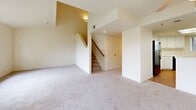 Located at 2505 5th St in Davis, CA, this two-story home offers four bedrooms, five bathrooms, and a thoughtfully arranged layout spread across two floors. The main level features a combined dining and living room with plush carpeting, a ceiling fan, and sliding glass doors that open onto a private balcony overlooking a lush outdoor setting. The kitchen is well-appointed with white cabinetry, light countertops, hardwood-style flooring, and black appliances including a range, microwave, dishwasher, and refrigerator. A pass-through counter connects the kitchen to the living area, promoting an open flow throughout the main level. Staircases with wood railings lead to the upper floor, where the bedrooms are situated. Each bedroom features soft carpeting, ceiling fans, and natural light through ample windows. The primary bedroom offers generous proportions with views of the surrounding neighborhood. The five bathrooms are finished with clean white fixtures, including tub-shower combinations and white vanities with built-in storage. Additional conveniences include a dedicated laundry room, multiple closets, and hallways connecting the spaces efficiently. The home's neutral palette and practical finishes create a bright, functional living environment throughout.
