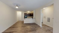 This single-floor residence offers a thoughtfully designed open-concept layout that connects the living, dining, and kitchen areas seamlessly. The main living area features wood-style plank flooring and a ceiling fan with light fixture, while a set of glass-paned doors allows natural light to flow in and provides outdoor access. A pendant light fixture accents the dining space adjacent to the kitchen.

The kitchen is a standout feature, equipped with dark espresso cabinetry, granite countertops, and black appliances including an electric range, over-the-range microwave, and refrigerator. A peninsula with bar seating creates a functional transition between the kitchen and living area.

The bedroom is carpeted for comfort and includes a ceiling fan, a window with blinds, and ample space for furnishings. A dedicated utility closet houses the water heater, keeping mechanical components neatly contained.

The bathroom features wood-style flooring consistent with the rest of the home, a dark vanity with granite countertop, and a full tub-shower combination. Neutral wall tones and clean white trim throughout the residence create a cohesive, modern aesthetic.