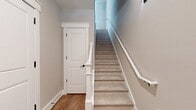 This two-story residence offers 1400 square feet of thoughtfully designed living space. The home features two bedrooms, including a generous 180 square foot primary bedroom, and three bathrooms for added convenience. The ground floor spans 690 square feet, while the upper level provides 710 square feet of space.

The interior showcases an open-concept layout, as evidenced by the combined kitchen and living room area. The living space is characterized by its bright and airy atmosphere, enhanced by large windows that flood the room with natural light. Gleaming hardwood floors extend throughout, adding warmth and elegance to the space.

The room's aesthetic is further elevated by clean, white walls and crown molding, creating a fresh and modern ambiance. A ceiling fan with light fixture provides both illumination and air circulation, contributing to the overall comfort of the space. The staircase, partially visible in the image, features white-painted balusters and newel post, seamlessly integrating with the room's design.

This home's layout also includes practical spaces such as a hallway and two closets, ensuring ample storage options. The entrance area welcomes residents and guests alike, setting the tone for the rest of the home. With its blend of style, comfort, and functionality, this residence offers a desirable living environment in a compact yet well-designed package.