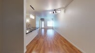 This single-floor residence offers a thoughtfully designed layout that balances comfort and functionality. The open living area is defined by warm, polished hardwood flooring that extends throughout the main living space, complemented by track lighting that adds a modern touch. Large windows allow natural light to filter in, enhancing the bright, airy atmosphere of the room.

The kitchen is well-equipped and features rich wood cabinetry, dark granite countertops, and stainless steel appliances including a refrigerator, range, and microwave. A peninsula with an undermount sink and pendant lighting above serves as both a prep area and a casual dining space, opening directly to the living area for a seamless flow.

The bedroom is carpeted for added comfort and includes a generously sized walk-in closet with built-in shelving and hanging rods, offering ample storage. A large window with blinds provides natural light and views of surrounding greenery, while a baseboard heater ensures year-round comfort.

The bathroom is clean and functional, featuring light vinyl flooring, a wood vanity with dark granite countertop, and a full tub and shower combination with a curtain rod and brushed nickel fixtures. The neutral color palette throughout the residence creates a cohesive and welcoming environment.