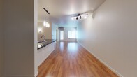 This single-floor residence offers a thoughtfully designed layout that balances comfort and functionality. The open living area is defined by warm, polished hardwood flooring that extends throughout the main living space, complemented by track lighting that adds a modern touch. Large windows allow natural light to filter in, enhancing the bright, airy atmosphere of the room.

The kitchen is well-equipped and features rich wood cabinetry, dark granite countertops, and stainless steel appliances including a refrigerator, range, and microwave. A peninsula with an undermount sink and pendant lighting above serves as both a prep area and a casual dining space, opening directly to the living area for a seamless flow.

The bedroom is carpeted for added comfort and includes a generously sized walk-in closet with built-in shelving and hanging rods, offering ample storage. A large window with blinds provides natural light and views of surrounding greenery, while a baseboard heater ensures year-round comfort.

The bathroom is clean and functional, featuring light vinyl flooring, a wood vanity with dark granite countertop, and a full tub and shower combination with a curtain rod and brushed nickel fixtures. The neutral color palette throughout the residence creates a cohesive and welcoming environment.