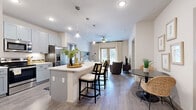 Located in Georgetown, TX, this well-appointed 2-bedroom, 2-bathroom residence offers a thoughtfully designed open-concept layout finished with wood-style flooring throughout. The kitchen is a standout feature, showcasing light gray shaker-style cabinetry, a stainless steel refrigerator, a spacious island with bar seating, and pendant lighting—flowing seamlessly into a dedicated dining area and a bright living room. The living room is bathed in natural light from large windows and French doors, complemented by a ceiling fan for year-round comfort. The primary bedroom is a generous retreat with large windows, a ceiling fan, and direct access to an en-suite bathroom. The primary bath features a dual-sink vanity with blue-gray cabinetry, a soaking tub, a separate glass-enclosed shower, wood-style flooring, and a walk-in closet. The second bedroom offers ample natural light and versatility, ideal as a guest room or home office. The second bathroom also includes a vanity with matching cabinetry and a tub-shower combination with walk-in closet access. A dedicated in-unit laundry area with a washer and dryer adds everyday convenience. Both closets provide organized storage solutions throughout this well-designed home.