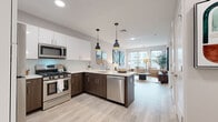 This single-floor, one-bedroom, one-bathroom residence in Hartford, CT offers a thoughtfully designed open-concept layout that seamlessly connects the kitchen, dining, and living areas. The kitchen is a standout feature, outfitted with stainless steel appliances including a gas range, microwave, dishwasher, and refrigerator. Two-toned cabinetry pairs crisp white upper cabinets with rich dark lower cabinets, complemented by a subway tile backsplash and light quartz countertops. A peninsula with seating provides additional dining and prep space, while stylish pendant lights hang overhead. Light wood-tone flooring extends throughout the main living areas, enhancing the bright, airy atmosphere created by large windows that invite natural light into the living room. The bedroom features plush carpeting, a generous window with exterior views, and ample wall space. The bathroom is finished with a white vanity, large-format tile flooring, and a glass-enclosed walk-in shower with white subway tile surround, delivering a clean, modern aesthetic throughout.