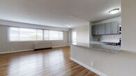 Located at 515 Mt Prospect Ave in Newark, NJ, this single-floor unit offers a clean, modern aesthetic throughout. The open-concept living and kitchen area is anchored by warm hardwood-style flooring that extends seamlessly across the space, creating a cohesive and inviting atmosphere. A bank of wide windows along the living room wall floods the area with natural light, while a baseboard heating unit ensures year-round comfort.

The kitchen is thoughtfully designed with gray shaker-style cabinetry, granite-look countertops, and a classic subway tile backsplash. A peninsula with a raised granite counter serves as a natural divider between the kitchen and living area, offering additional workspace and casual seating potential. Stainless steel appliances, including a microwave, gas range, and dishwasher, complete the kitchen alongside a full-size refrigerator.

The bedroom features the same hardwood-style flooring, a window with blinds for natural light and privacy, and a built-in closet with sliding doors. The bathroom is finished with white tile flooring, a dark-toned vanity with an integrated sink, and a mirrored medicine cabinet above. The entry area provides direct access to the main living space, rounding out a functional and well-designed layout.