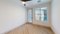 Located at 1734 W Desert Hollow Dr in Phoenix, AZ, this well-appointed one-bedroom, one-bathroom unit offers a thoughtfully designed layout across a single floor. The open-concept kitchen and living area serves as the heart of the home, showcasing light wood-tone flooring, crisp white walls, and abundant recessed lighting. The kitchen is outfitted with stainless steel appliances, including a French door refrigerator, range, and built-in microwave, complemented by two-tone cabinetry in warm wood and charcoal finishes. A standout navy blue island with a white quartz countertop and undermount sink anchors the space, illuminated by a pair of modern pendant lights. The bedroom features plush carpeting, a ceiling fan, and a window with outdoor views, creating a comfortable and airy retreat. Direct balcony access adds an additional outdoor living option. The walk-in closet provides generous built-in shelving and dual hanging rods for well-organized storage. The bathroom is finished with wood-look flooring, a framed mirror, under-mount sink with modern fixtures, and a tub-shower combination. Clean lines and a neutral palette give this unit a cohesive, modern aesthetic throughout.