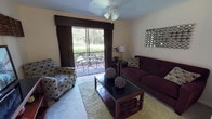 Located at 1002 Bristol Lake Rd in Mt Dora, Florida, this single-story residence offers a well-organized layout with comfortable living spaces throughout. The living room serves as the heart of the home, featuring a ceiling fan, plush carpeting, and a large sliding glass door that opens to a private balcony overlooking lush, green surroundings — filling the space with natural light and serene outdoor views. The galley-style kitchen is outfitted with white cabinetry, dark countertops, a double sink, and white appliances including a refrigerator and electric range, providing efficient functionality. Adjacent to the kitchen, the dining area comfortably accommodates a full dining set and conveniently includes an in-unit laundry closet with a full-size washer and dryer. The primary bedroom is bright and spacious, with a ceiling fan, large window with sheer curtains, and soft carpeting, creating a restful retreat. A second bedroom offers a cozy, carpeted space with a closet and natural light. The full bathroom features a wide vanity with ample counter space, a large mirror, and a shower/tub combination, finished with light tile flooring. This residence combines practical amenities with a relaxed Florida ambiance.