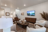 Located in Heber City, Utah, this two-story home offers a thoughtfully designed interior with a clean, modern aesthetic carried throughout both levels. The main floor features an inviting living area with light hardwood flooring, recessed lighting, and warm neutral tones that create a welcoming atmosphere. A wall-mounted television, a walnut media console, and a mix of leather and upholstered seating anchor the space with a blend of comfort and style. Natural light flows in through well-placed windows dressed in linen curtains. The kitchen is well-appointed with grey shaker cabinetry, dark stone countertops, stainless steel appliances, and a central island with bar seating — ideal for both everyday meals and entertaining. Upstairs, the bedrooms provide comfortable retreats, each featuring plush carpeting, ample natural light from multiple windows, and tasteful décor. The bathrooms are finished with marble-look tile flooring, white subway tile tub surrounds, matte black fixtures, and clean white vanities, delivering a polished and cohesive look. A central staircase connects the two levels, reinforcing the home's efficient and functional layout. Throughout, the design balances modern simplicity with warm, livable character.