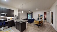 This contemporary single-floor residence offers a thoughtfully designed open-concept layout that seamlessly connects the kitchen, dining, and living areas. The gourmet kitchen is a standout feature, showcasing dark espresso cabinetry extending to the ceiling, quartz countertops, a central island with an undermount sink, stainless steel appliances including a French door refrigerator and range with microwave, and elegant pendant lighting. The open dining and living area extends naturally from the kitchen, with wood-look luxury vinyl flooring, recessed lighting, and a ceiling fan overhead. A sliding glass door leads to a private outdoor balcony, filling the living space with natural light.

The primary bedroom features a rich accent wall, large-format artwork, and direct access to the balcony through a sliding glass door, creating a seamless indoor-outdoor connection. The secondary bedroom is equally well-appointed, with a bold accent wall, large window with outdoor views, and plush carpeting.

The primary bathroom impresses with a dual-sink vanity, dark cabinetry with ample storage, a large mirror, and a sleek walk-in shower clad in marble-style tile. The secondary bathroom offers a single-sink vanity with matching dark cabinetry and a tiled tub-shower combination. Throughout, the design maintains a cohesive modern aesthetic with clean lines, neutral tones, and upscale finishes.