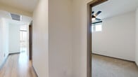 Located at 777 E 17th Ave in Denver's vibrant Capitol Hill neighborhood, this contemporary 2-bedroom, 1-bathroom unit offers a well-designed open-concept layout across a single floor. The living area is immediately striking, featuring expansive floor-to-ceiling windows on two walls that flood the space with natural light and frame panoramic views of the Denver skyline and surrounding cityscape. Light hardwood flooring runs throughout the main living area, complemented by a ceiling fan overhead.

The kitchen is a standout feature, showcasing a large quartz-topped center island with an integrated sink and sleek matte black fixtures. White flat-panel cabinetry extends to the ceiling, paired with a white subway tile backsplash and stainless steel appliances, including a refrigerator, range, and microwave. Track lighting above adds a modern industrial touch.

Both bedrooms are finished with plush carpet and feature paneled gray doors with black hardware. The primary bedroom includes access to a dedicated closet with built-in shelving. Each bedroom benefits from natural light via large windows offering urban views.

The bathroom is elegantly finished with light hardwood flooring, a full-width vanity with a white countertop, matte black fixtures, a large mirror, and a full tub-shower combination with white subway tile surround.