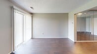 Located at 2703 S Topeka St in Wichita, KS, this 2-bedroom, 1-bathroom unit offers a practical and well-organized single-floor layout. The living room provides a comfortable gathering space with wood-style flooring, neutral walls, a textured ceiling, and a large sliding glass door fitted with vertical blinds that floods the room with natural light. The kitchen is equipped with warm oak cabinetry, light laminate countertops, a double-basin sink, a white electric range, and a dishwasher, along with a window that brings in additional daylight. Wood-style flooring continues from the kitchen into a connecting hallway that flows seamlessly back toward the living area. Both bedrooms feature plush carpeting and textured ceilings. The primary bedroom includes a sliding glass door with vertical blinds, while the second bedroom offers a window with blinds and generous closet space with bifold doors. Additional storage is available via a hallway closet. The bathroom includes a vanity with a light countertop, mirror with storage cabinet, and a clean, functional layout. Throughout the unit, a consistent neutral color palette and thoughtful floor plan create a cohesive and livable environment.