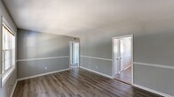 Located at 3151 Harris Dr in East Point, GA, this single-floor, one-bedroom, one-bathroom home offers a well-organized and functional layout. The interior is finished with durable hardwood-style flooring and a consistent cool gray color palette, accented by crisp white trim and chair rail molding that runs throughout the main living areas, lending a clean and cohesive aesthetic.

The living room is a generous, open space filled with natural light from a large multi-pane window. A front entry door provides direct access, and the room flows easily into the rest of the home via a connecting hallway.

The kitchen is well-appointed with white cabinetry extending to the ceiling for ample storage, granite-look countertops, and a full suite of stainless steel appliances including a refrigerator, range, and over-the-range microwave. A secondary exterior door and window in the kitchen area bring in additional natural light.

The bedroom is a comfortable, well-proportioned room featuring a ceiling fan, a natural light-filled window with an outdoor view, and a set of bifold closet doors providing convenient storage. The bathroom includes a full tiled tub-and-shower combination with classic white tile surround. A hallway connects all areas of the home, completing this practical and neatly finished single-story residence.