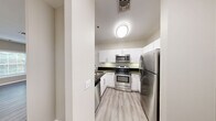 This well-appointed two-bedroom, two-bathroom residence at 33 Railroad Avenue in Milford, Connecticut offers a thoughtfully designed single-floor layout. The open kitchen and living area serves as the heart of the home, featuring crisp white cabinetry with sleek bar-pull hardware, dark granite countertops, a breakfast bar peninsula, and a full suite of stainless steel appliances including a range, microwave, dishwasher, and refrigerator. Light wood-toned luxury vinyl plank flooring runs throughout the main living areas, lending a clean, contemporary feel. The living room receives generous natural light through large windows with views of lush greenery. Both bedrooms are carpeted and offer a calm, neutral palette with warm greige walls and bright white trim. The spacious primary bedroom includes a dedicated walk-in closet outfitted with wrap-around wire shelving. The bathrooms are finished with white tile flooring, dark granite vanity tops, white cabinetry, and glass-enclosed tub-shower combinations. A hallway connects the private quarters to the main living space, maintaining a practical and organized flow throughout the residence.