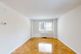 Located at 8200 Wisconsin Ave in the heart of Bethesda, MD, this one-bedroom, one-bathroom unit offers a practical and well-organized layout across a single floor. Polished parquet wood flooring runs throughout the main living areas, hallway, and bedroom, lending a warm, classic character to the space.

Entry is through a clean, narrow hallway that opens into the combined living and dining area — a bright, open space illuminated by sliding windows that frame views of the surrounding Bethesda neighborhood. A ceiling fan overhead and a baseboard radiator provide year-round comfort.

The kitchen features warm wood cabinetry with decorative raised-panel detailing, granite-style countertops, a double-basin sink, a gas range, and a full-size refrigerator. Light tile flooring completes the kitchen's functional design.

The primary bedroom is a well-proportioned room with its own window and polished parquet floors, offering a comfortable and quiet retreat. A dedicated closet provides convenient storage.

The bathroom includes a wood-toned vanity with a white countertop sink, a tiled shower/tub combination, and tile flooring, maintaining a clean and neutral aesthetic throughout. The unit also includes a hallway closet for additional storage.