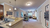 Located at 11321 Colbert Creek Loop in Raleigh, NC, this single-floor residence offers a well-designed, open-concept layout that seamlessly connects the main living areas. The kitchen is outfitted with rich wood cabinetry, granite countertops, black appliances including an electric range and built-in microwave, and a subway tile backsplash. A breakfast bar with pendant lighting provides additional seating and transitions naturally into the dining area. Tile flooring runs through the kitchen, while plush carpeting extends throughout the living and bedroom areas. The living room is bright and welcoming, featuring crown molding, a ceiling fan, and multiple windows that invite natural light. The primary bedroom is generously sized with a ceiling fan, walk-in closet, and a private en-suite bathroom complete with a wood vanity and well-lit mirror. Additional bedrooms offer comfortable proportions with ample natural light and closet space. The bathrooms are finished with tile flooring, including one featuring a soaking tub with full tile surround. A dedicated laundry area adds everyday convenience. Throughout, neutral tones and consistent finishes create a cohesive and functional living environment.