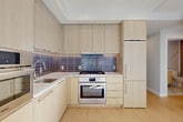 Located at 1224 M St NW in Washington, DC, this one-bedroom, one-bathroom residence offers a thoughtfully designed floor plan that maximizes every square foot. Light-toned hardwood flooring runs throughout, lending warmth and continuity to the space.

The open-concept living and dining area is bright and airy, benefiting from natural light that pours in through floor-to-ceiling glass doors leading to a private balcony — an ideal spot for taking in city views. The seamless transition between living and dining spaces creates a versatile, functional layout.

The kitchen is a standout feature, outfitted with flat-front light wood cabinetry extending to the ceiling for ample storage, a stylish dark tile backsplash, white quartz countertops, and a full suite of Bosch stainless steel appliances including a gas range, wall oven, microwave, and refrigerator.

The bedroom is a serene retreat with clean white walls, hardwood floors, and a window with a classic brick exterior view, complemented by a second glass door that invites additional natural light. Two closets provide generous storage throughout the unit.

The bathroom is finished with floor-to-ceiling vertical tile surrounding a soaking tub and shower combo, marble-look tile flooring, and clean chrome fixtures, creating a polished, spa-like feel.
