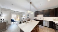 Located at 31 East Ogden Avenue in La Grange, IL, this well-appointed one-bedroom, one-bathroom unit offers a thoughtfully designed open-concept layout spread across a single floor. Light-toned wood-style flooring flows throughout the main living areas, complementing a neutral color palette that creates a bright, cohesive atmosphere.

The kitchen is a standout feature, showcasing rich dark espresso cabinetry with sleek hardware, crisp white quartz countertops, a classic white subway tile backsplash, and a full suite of stainless steel appliances including a dishwasher, microwave, and range. A center island with seating provides additional prep space and casual dining. A modern pendant light fixture adds an elegant finishing touch overhead.

The kitchen opens directly into the living room, which benefits from vaulted ceilings and abundant natural light streaming through large sliding glass doors. These doors lead to a private patio, extending the living space outdoors. The bedroom is a serene retreat with plush carpeting, soft neutral walls, and a window that invites natural light. Two closets offer generous storage throughout the unit. A dedicated laundry space adds everyday convenience, and the bathroom features dark cabinetry consistent with the home's cohesive modern design.