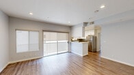 This thoughtfully designed 2-bedroom, 1-bathroom residence offers a functional and modern living experience across a single floor. The open-concept layout seamlessly connects the living room and kitchen, creating an inviting, airy atmosphere filled with natural light from sliding glass doors that lead to a private balcony. The living area features warm wood-look flooring, recessed lighting, and neutral gray walls that lend a clean, contemporary feel throughout.

The kitchen is a standout feature, boasting white cabinetry with sleek hardware, white quartz countertops, a decorative stone tile backsplash, and a full suite of stainless steel appliances including a gas range, microwave, dishwasher, and refrigerator. A peninsula provides additional workspace and casual seating.

The primary bedroom is a comfortable retreat with its own sliding glass door opening to a private balcony overlooking lush greenery. The second bedroom is well-sized with a window for natural light. Both rooms continue the wood-look flooring found throughout the home.

The bathroom is elegantly finished with large-format tile surrounding the tub and shower, a white vanity with modern fixtures, a wood-framed mirror, and built-in shelving. A hallway connects the private spaces efficiently, completing this well-organized and stylish home.